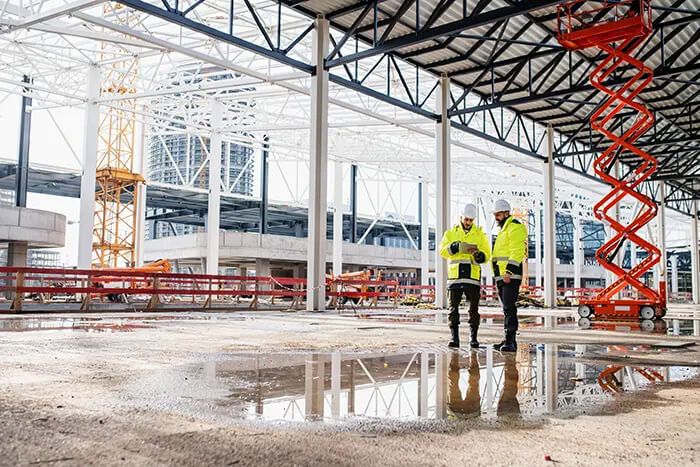 Two construction engineers stand in a construction site using an iPad.