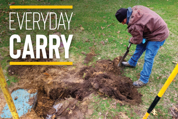 A technician working in the dirt with the words "EVERYDAY CARRY."